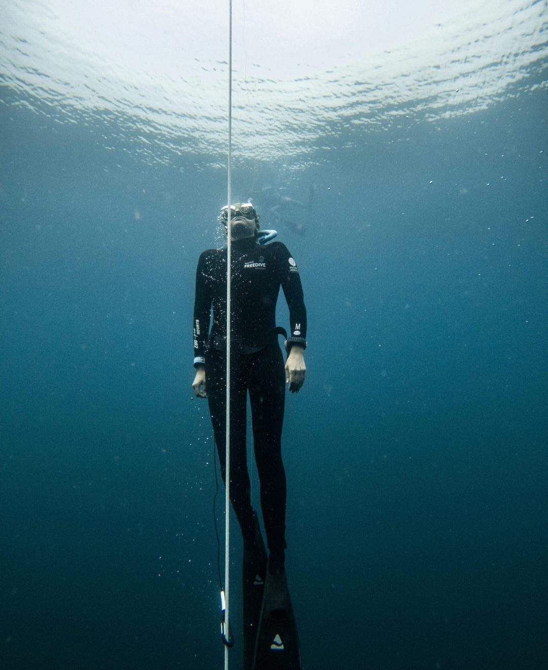 A freediver descends into the deep blue waters of Lombok, Indonesia, showcasing underwater exploration.